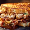 BBQ Chicken Grilled Cheese sandwich with melted cheese, smoky BBQ chicken, and crispy golden bread, served on a rustic wooden table.